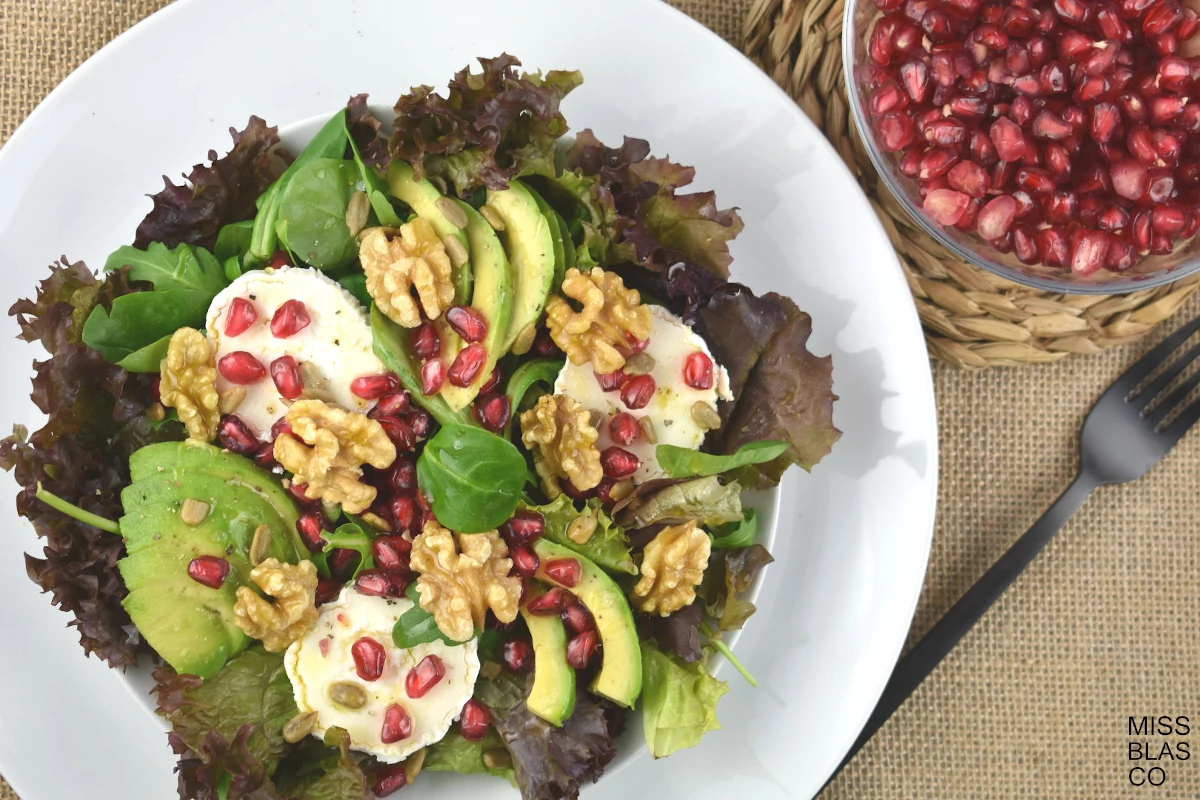 Pomegranate and Goat Cheese Salad in a white plate with a black fork