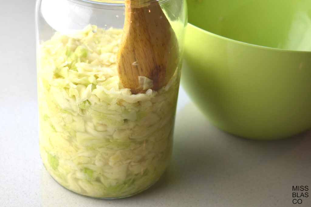 Cabbage in a glass jar with a wooden spoon