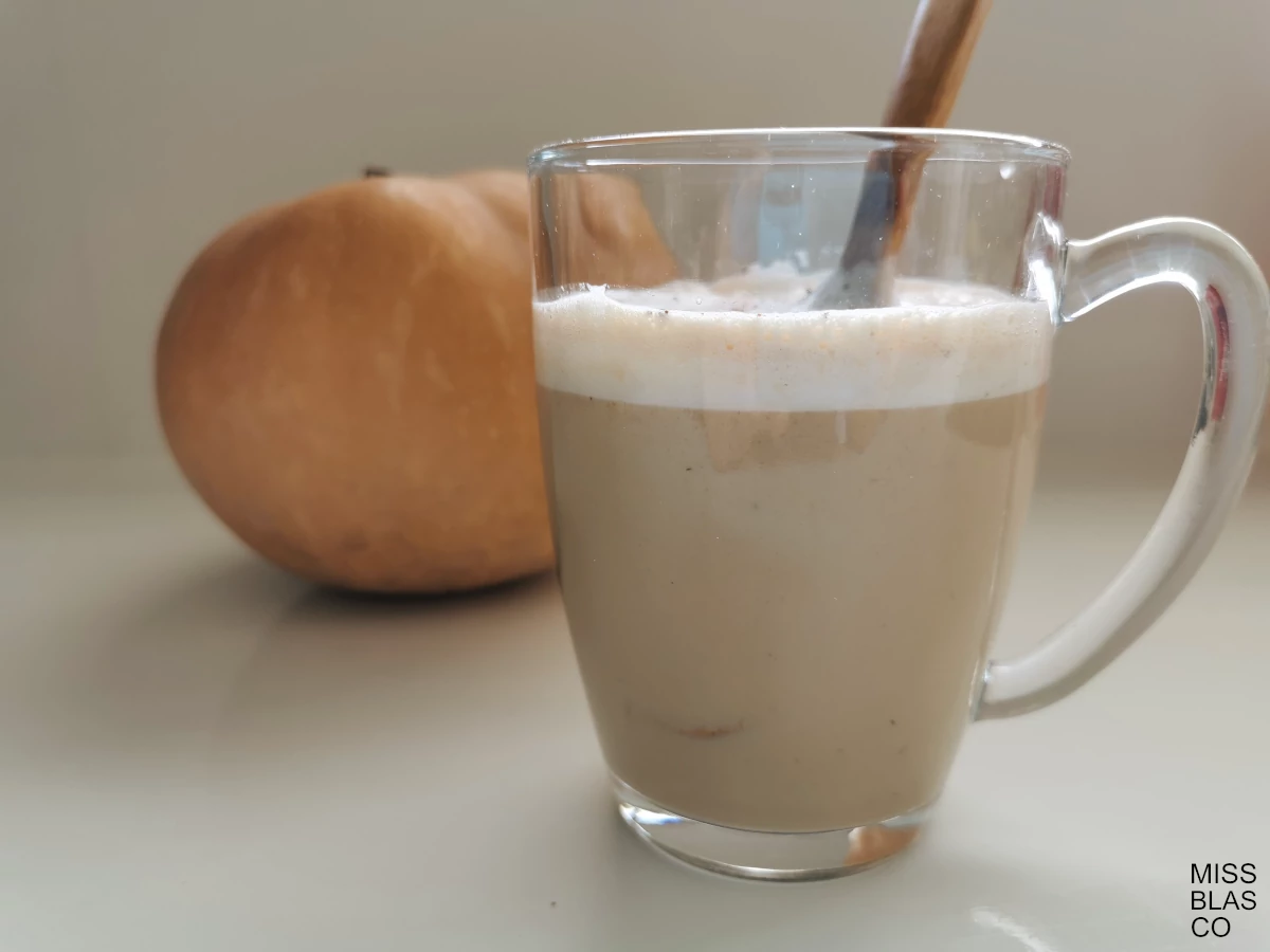 pumpkin spice latte in a glass cup with a wooden spoon