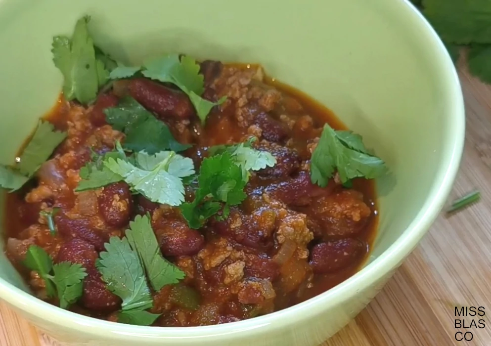 easy beef chili in a green bowl with cilantro leaves
